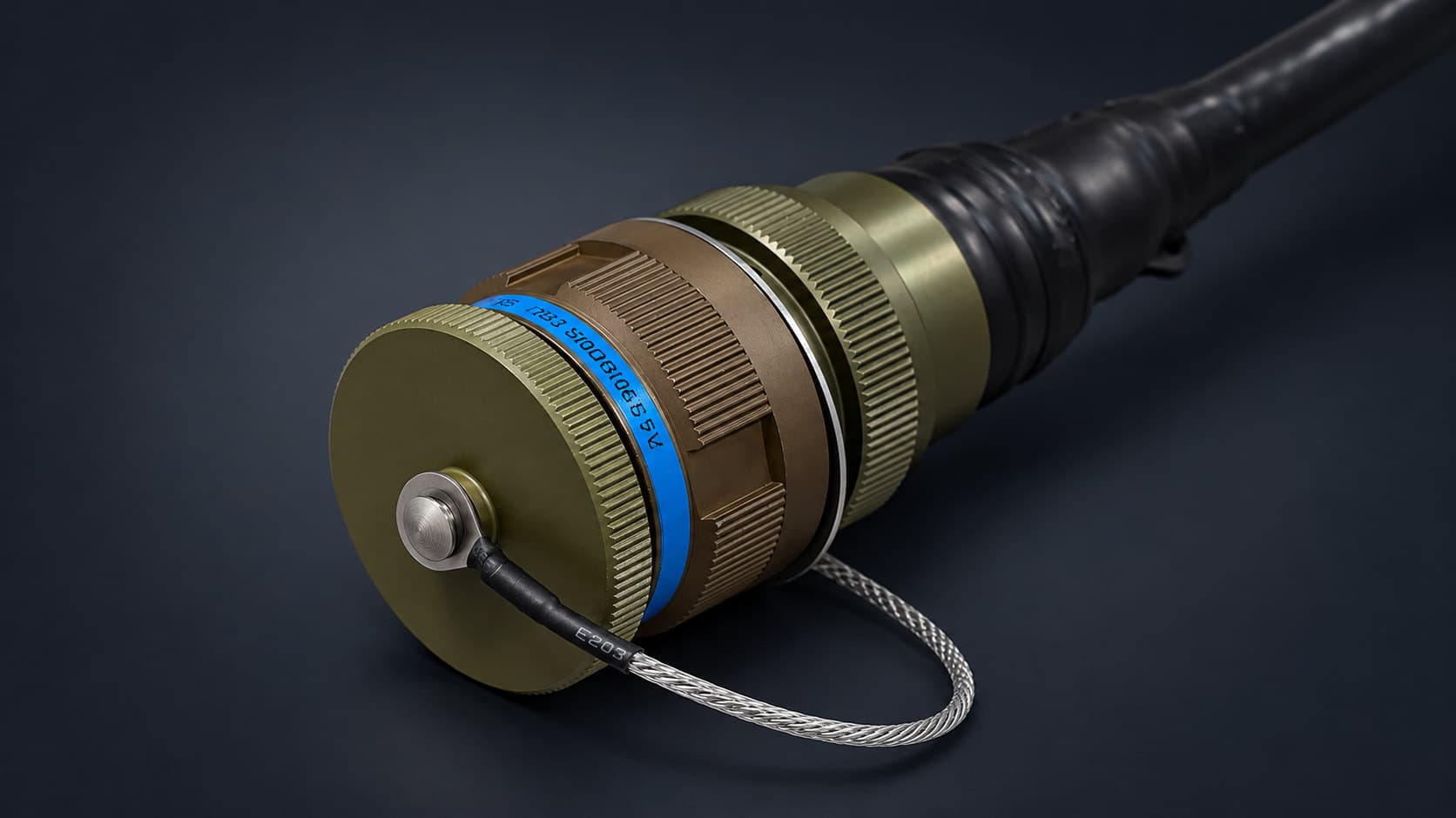 Olive-drab circular connector closed with its knurled dust cap on a braided lanyard, with a blue identification band and a black moulded boot on the cable behind